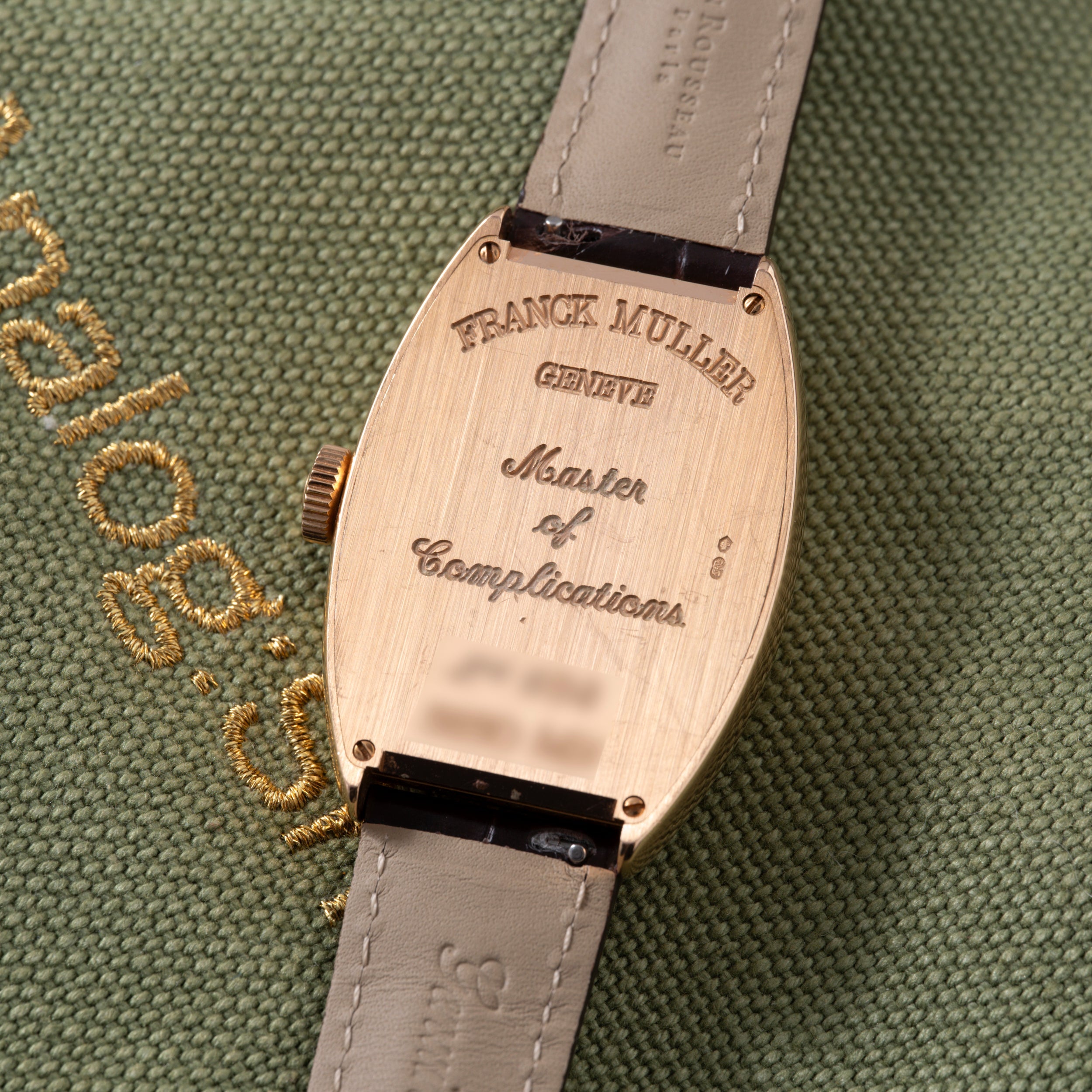Franck Muller Master of Complications watch with rose gold tonneau case and gray leather strap.