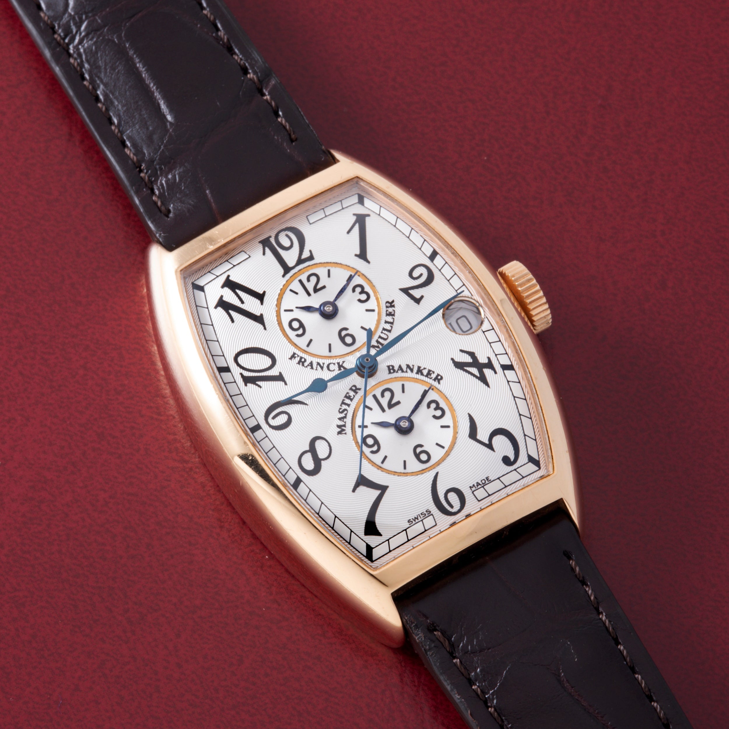 Rose gold tonneau watch with white dial, two subdials, Arabic numerals, and black leather crocodile-textured strap.
