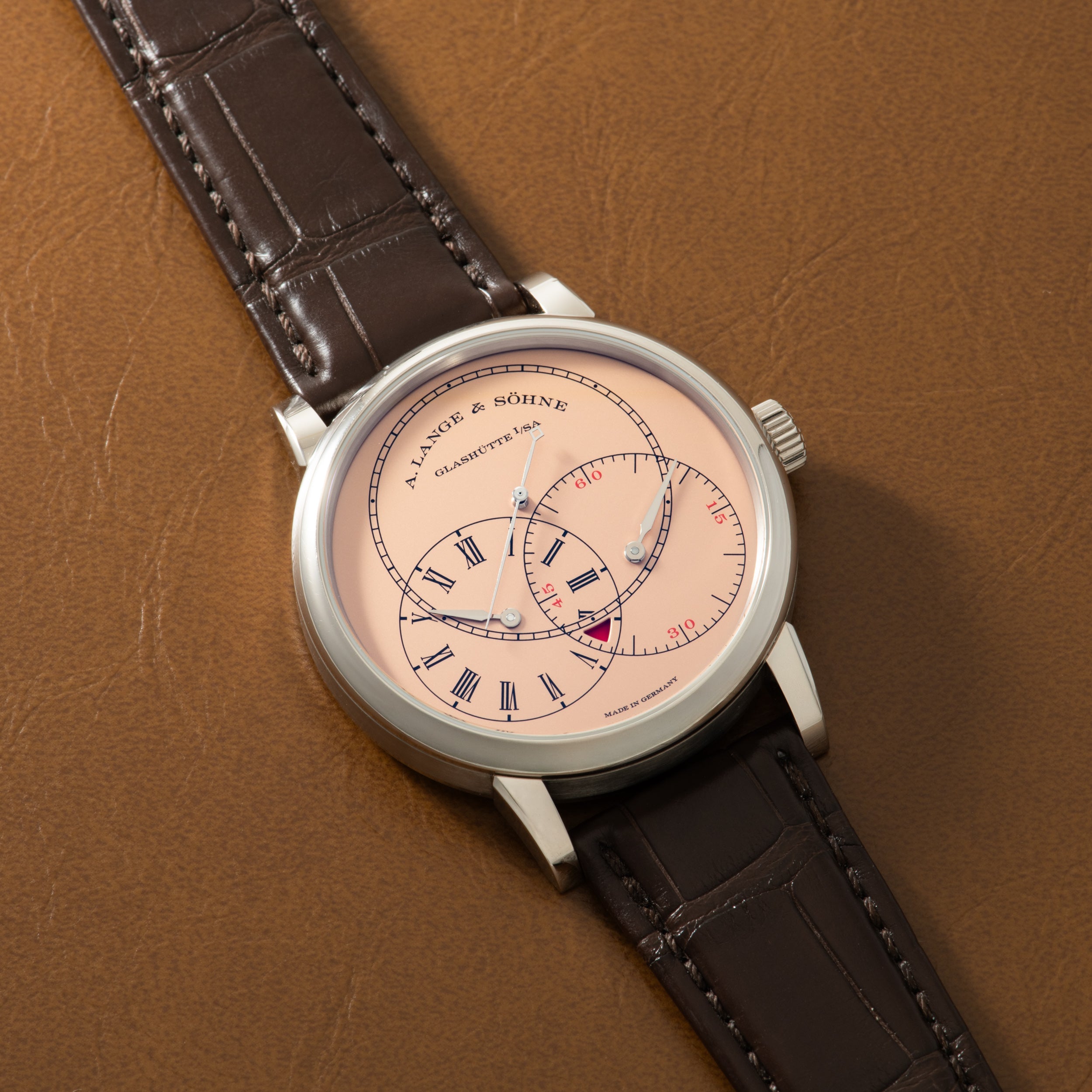 Silver-toned watch with cream dial, Roman numerals, circular subdial, and dark crocodile-textured leather strap.