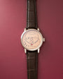 Silver-tone watch with cream dial, Roman numerals, dual subdials, and dark brown crocodile leather strap.