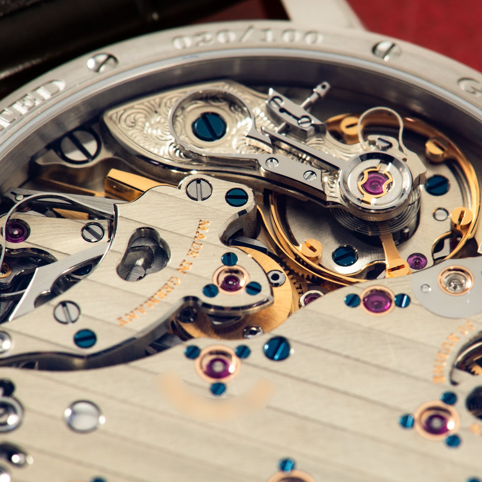 Close-up of watch movement showing polished steel bridge with jumping seconds mechanism and colorful jewels.