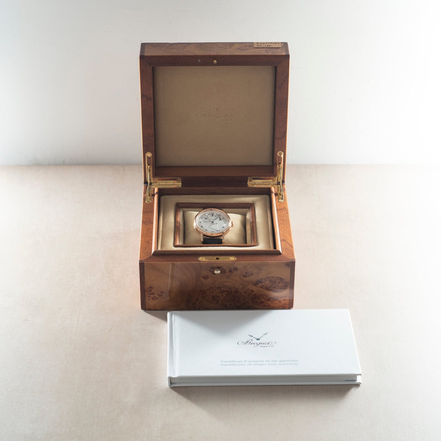 Breguet Classique watch with white dial and leather strap in open wood box with accompanying documentation.
