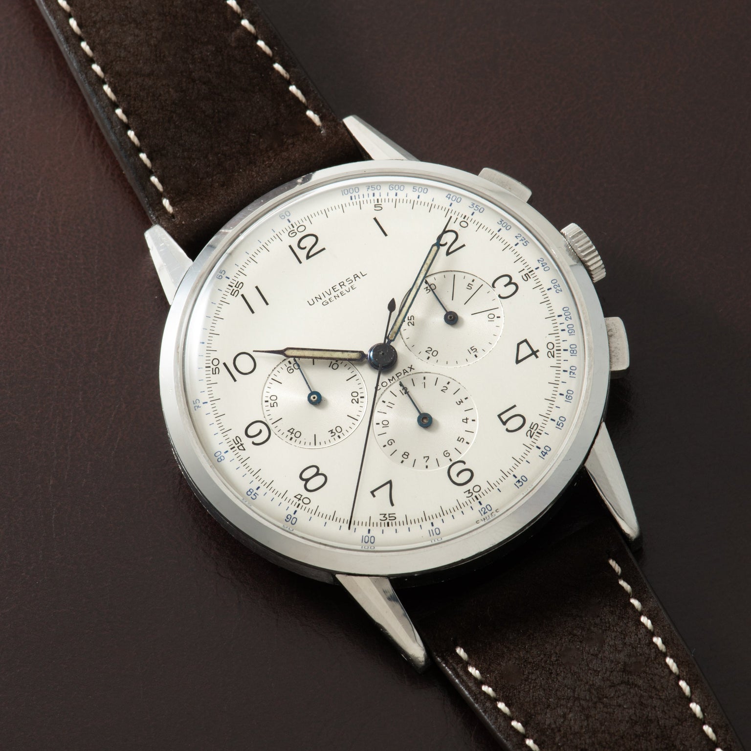 Stainless steel chronograph watch with cream dial, multiple subdials, black leather strap with white stitching.