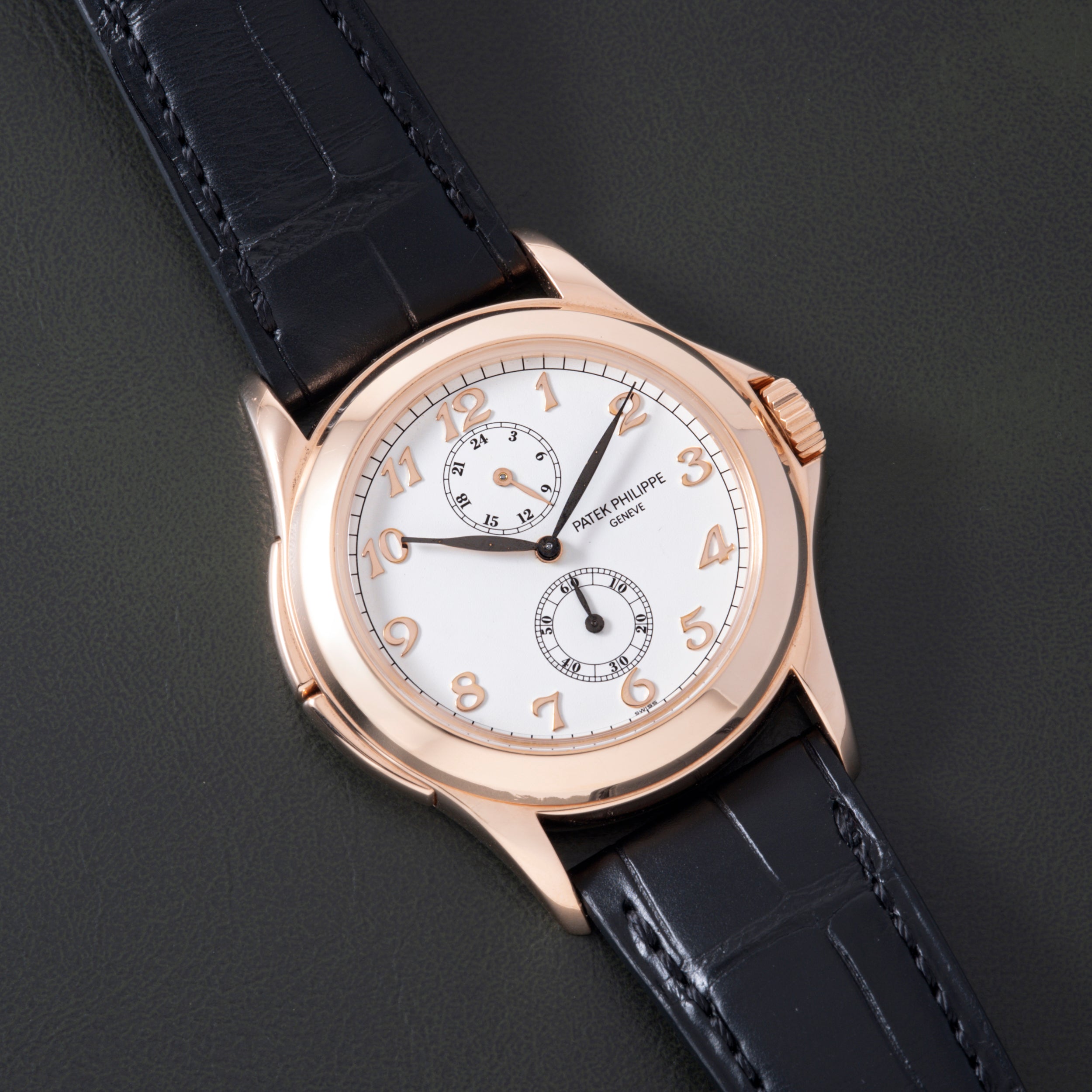 Rose gold round watch with white dial, Arabic numerals, two subdials, and black crocodile leather strap.