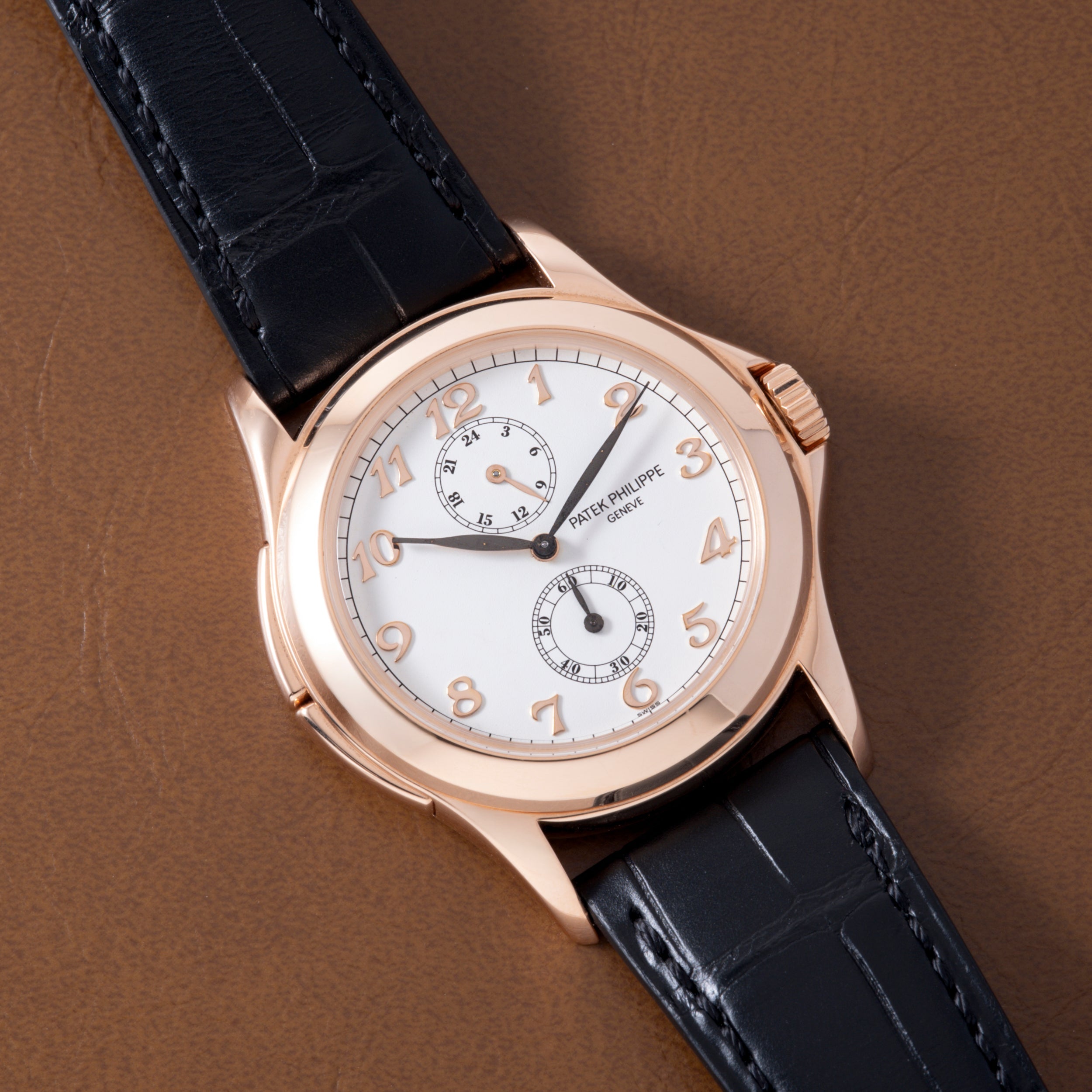 Rose gold watch with white dial, Arabic numerals, two subdials, and black crocodile leather strap.