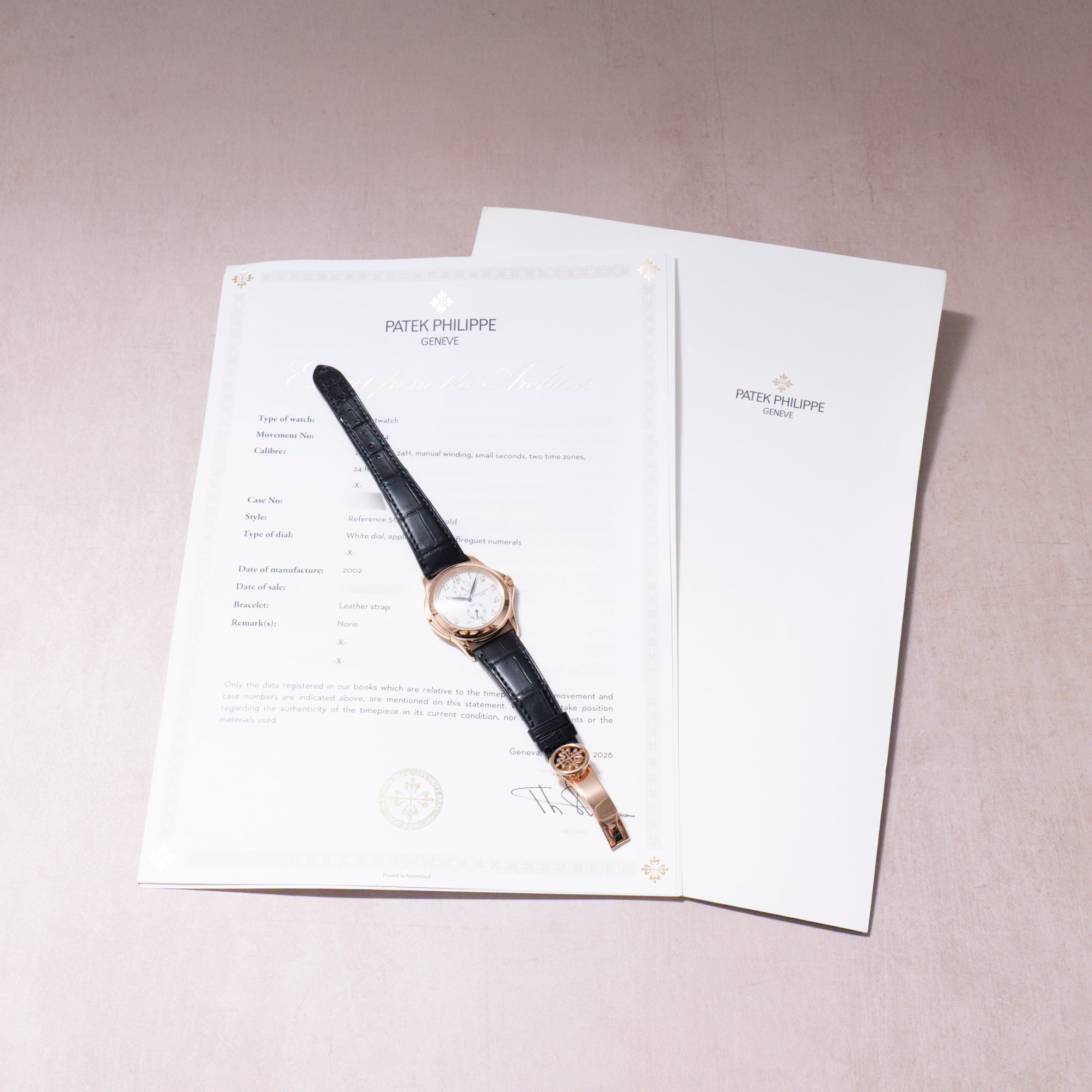 Patek Philippe Calatrava wristwatch with rose gold case, cream dial, and black leather strap displayed on documentation paper