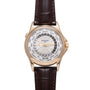 Rose gold watch with white dial displaying world city time zones, dark brown leather strap with stitching.