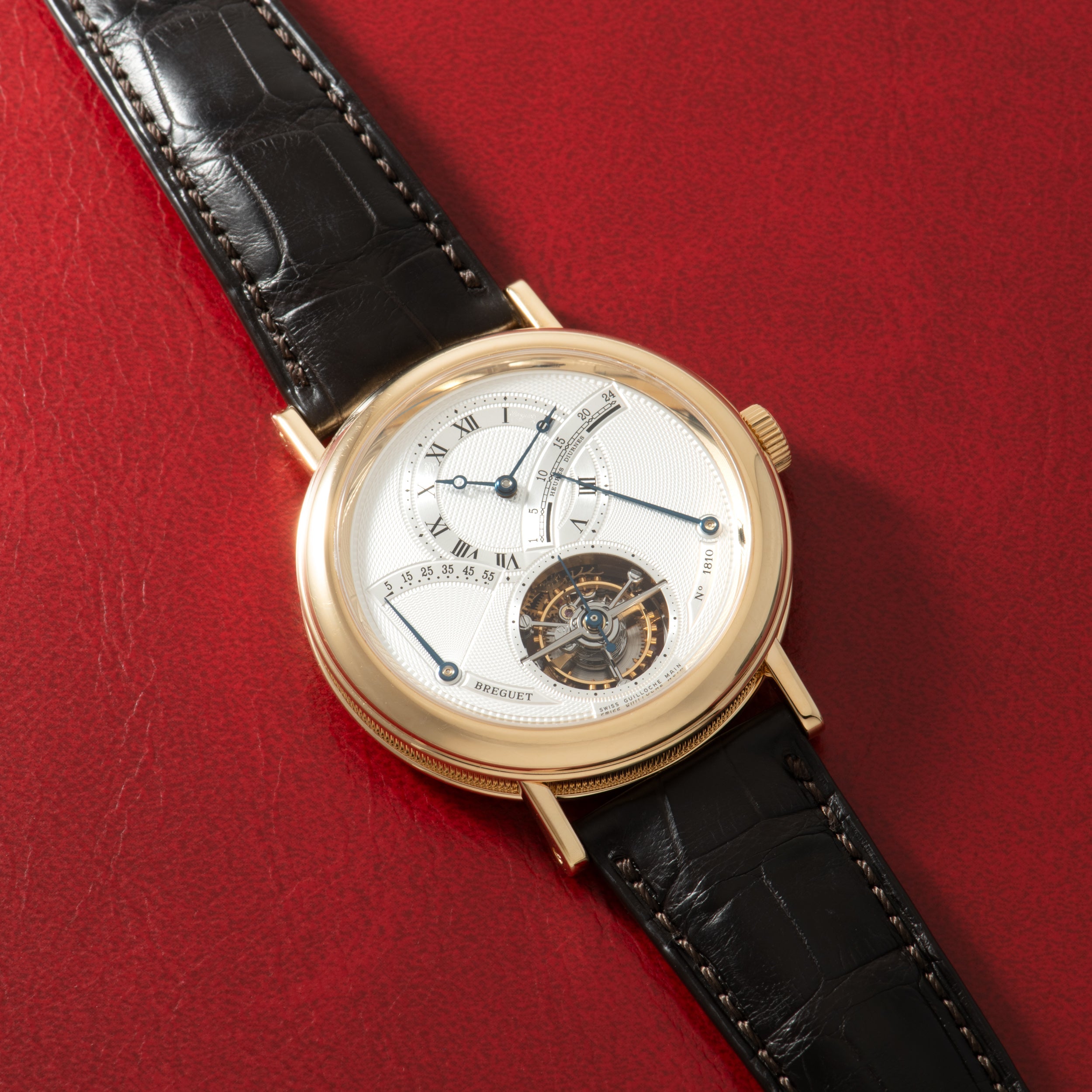 Gold-toned watch with white dial, Roman numerals, visible tourbillon at 6 o'clock, and black crocodile leather strap.
