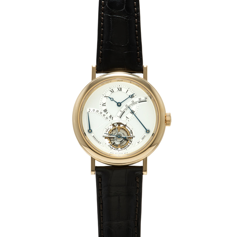 Gold-tone round watch with cream dial, tourbillon mechanism at bottom, Roman numerals, and black crocodile leather strap.