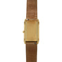 Gold-tone rectangular watch with brushed finish, side crown, and brown leather strap shown from the back.
