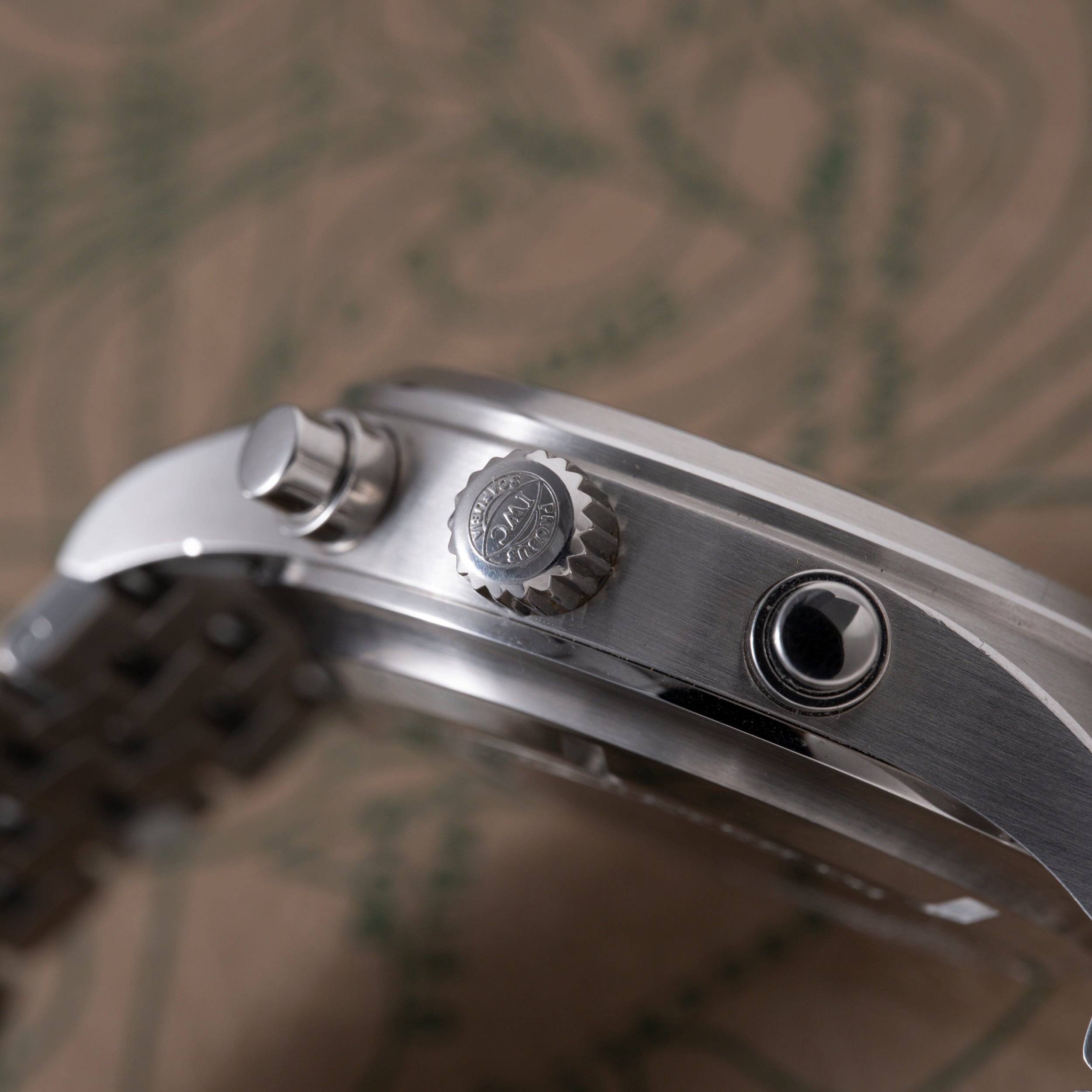 Stainless steel pilot's chronograph watch with brushed case, crown, and subdials visible from the side angle.