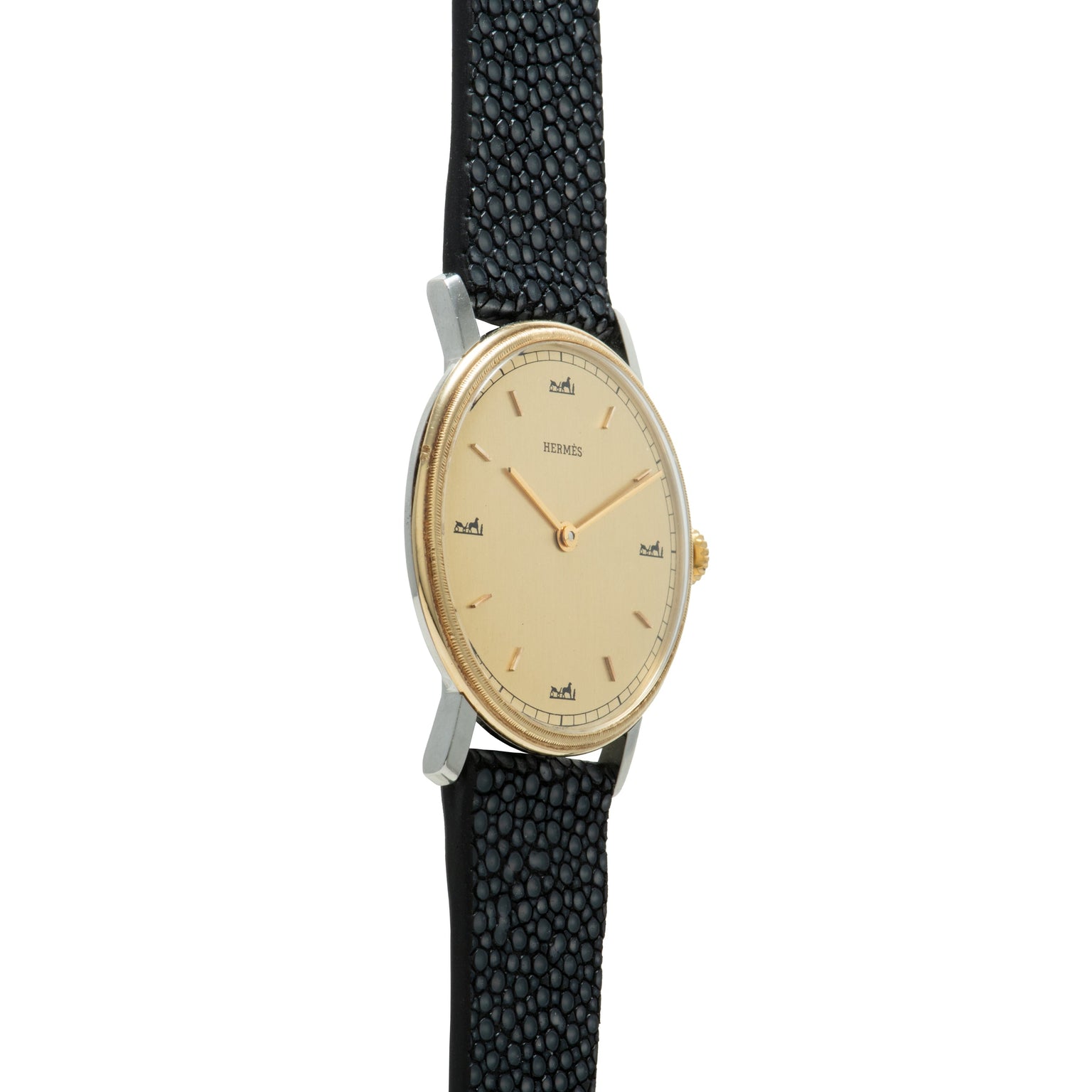 Hermès wristwatch with oval cream dial, gold-tone hands and indices, two-tone case, and black textured leather strap.