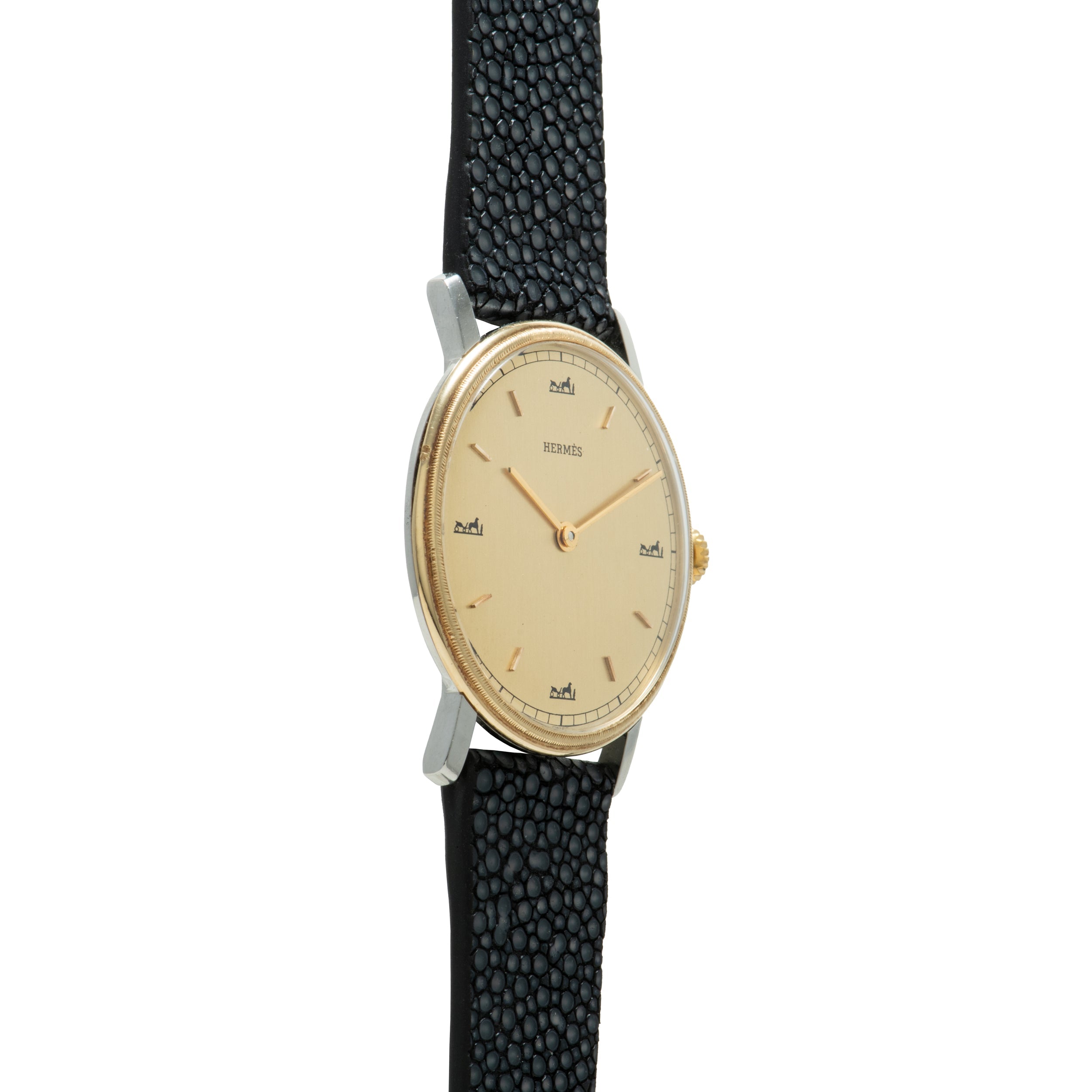 Hermès wristwatch with oval cream dial, gold-tone hands and indices, two-tone case, and black textured leather strap.