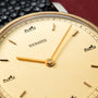 Hermès watch with cream dial, gold hands, hour markers, and carriage logo at 12 and 6 o'clock positions.