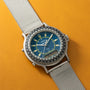 Yema Spationaute ISS watch with blue dial, luminous indices, rotating bezel, silver mesh strap, and digital subdial on yellow