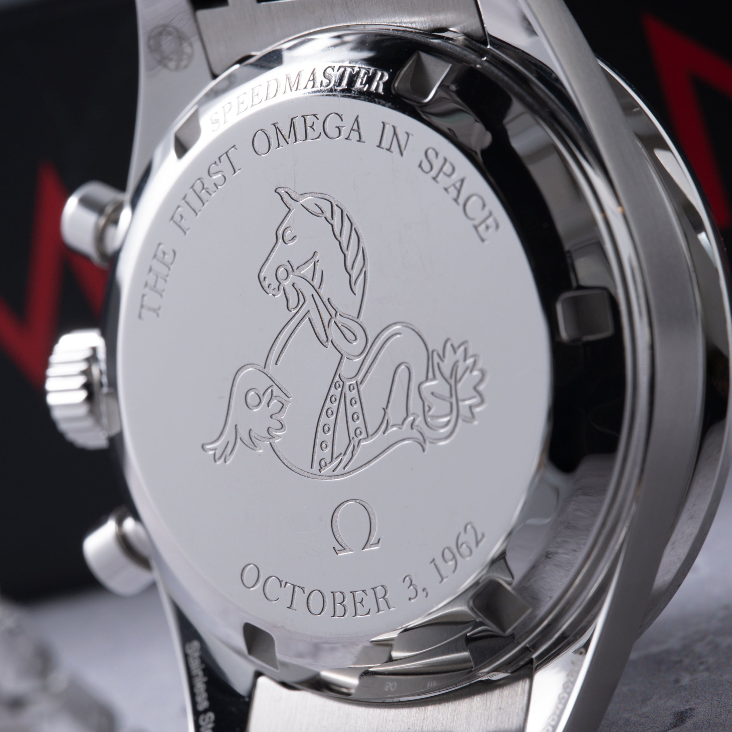 Omega Speedmaster watch back engraved with "The First Omega In Space" text, seahorse emblem, and October 3, 1962 date.