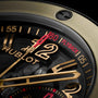 Watch face with gold and black dial, gold hands, red chronograph hand, and "60 FLYBACK" indicator on black bezel.
