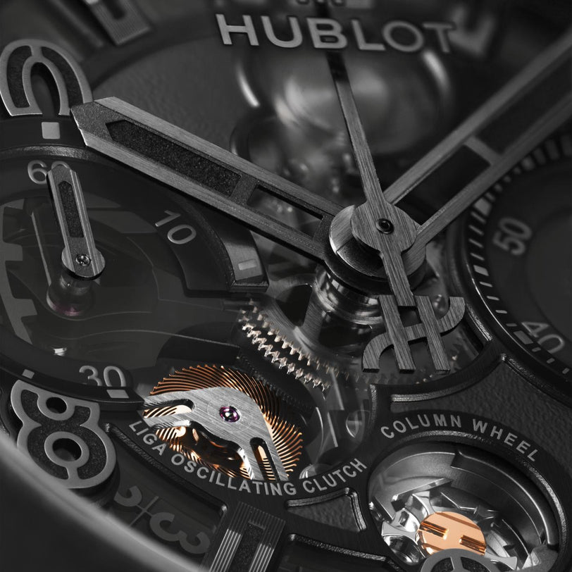Black watch with visible Hublot branding, skeleton dial showing mechanical movement with gold accents, and skeletal hour and 