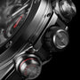 Titanium and ceramic chronograph watch with black dial, red accents, and metallic pushers shown in close-up detail.