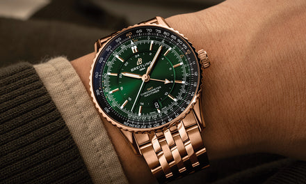 A Breitling Navitimer watch on a wrist with a brown shirt and sweater