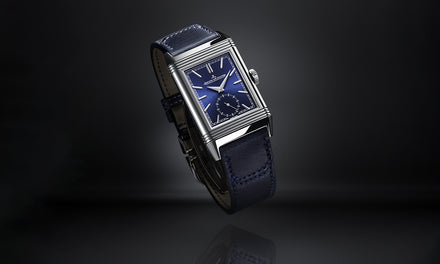A rectangular blue-faced wristwatch with a blue leather strap on a dark gradient background.