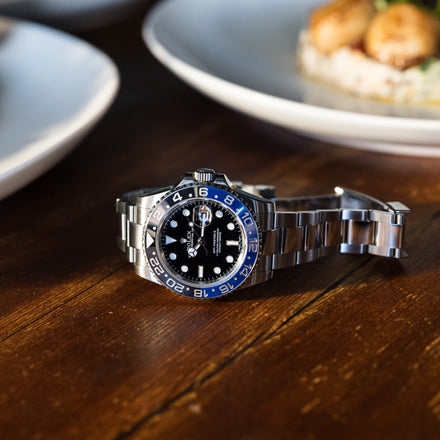 Rolex GMT Master II watch with black and blue bezel on a wooden table