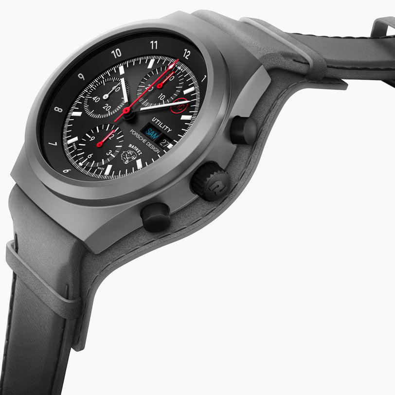 A close-up of the Porsche Design Chronograph 1 Utility Limited Edition, a black wristwatch with red hands, gray strap, detailed dials, and date display.