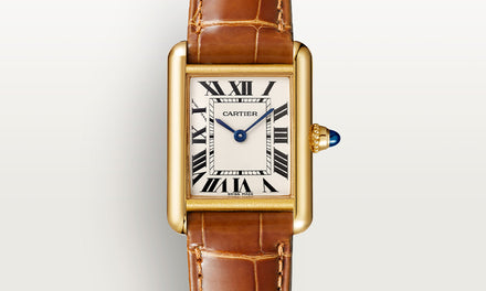 A close up view of the Cartier Tank watch with gold bezel and brown leather strap