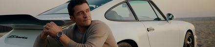 Man leaning against a white sports car on a beach