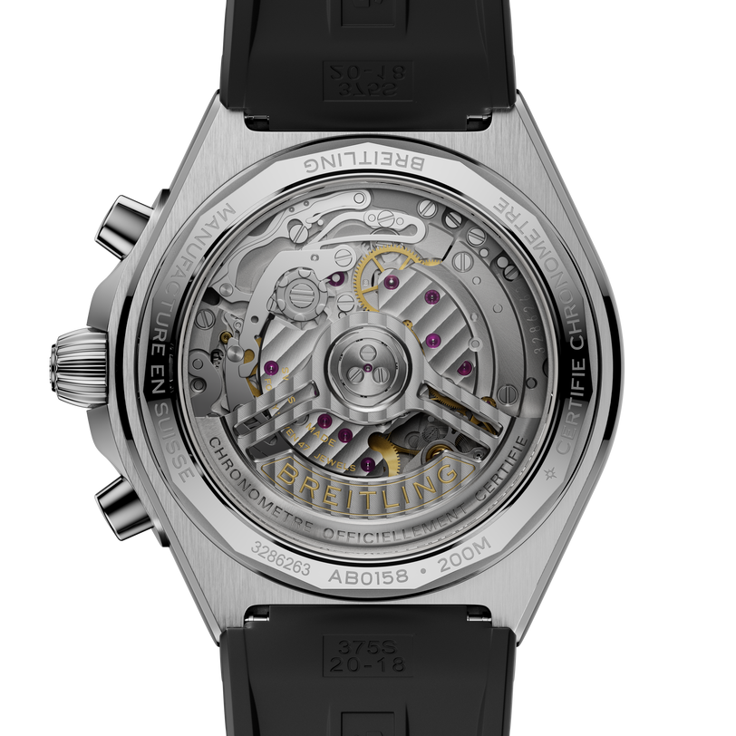 Stainless steel chronograph watch with visible mechanical movement, black rubber strap, and transparent caseback displaying j