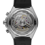 Stainless steel chronograph watch with visible mechanical movement, black rubber strap, and transparent caseback displaying j
