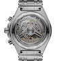 Stainless steel chronograph watch with visible mechanical movement through transparent caseback and linked metal bracelet.