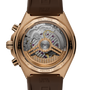 Rose gold watch with brown rubber strap and exposed mechanical movement visible through transparent case back.
