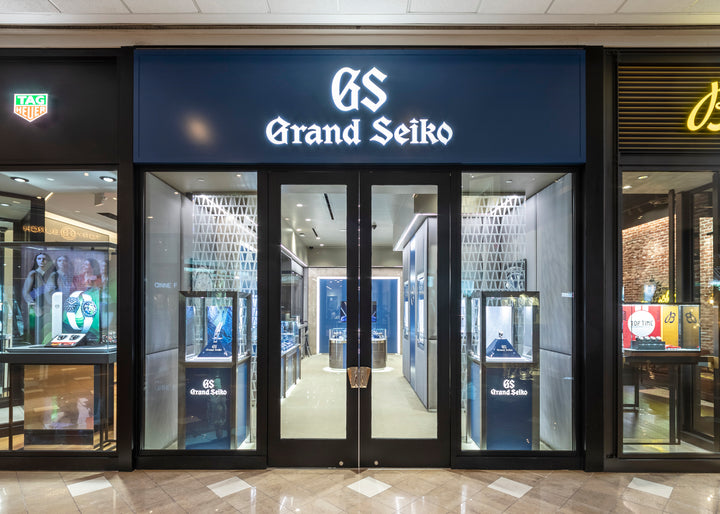 Grand Seiko store entrance with glass doors and illuminated signage in a shopping mall.