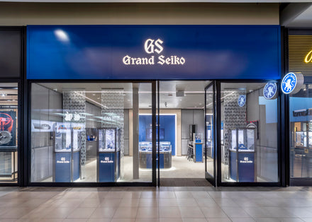 Grand Seiko store with blue signage, glass doors, and watch displays visible inside.