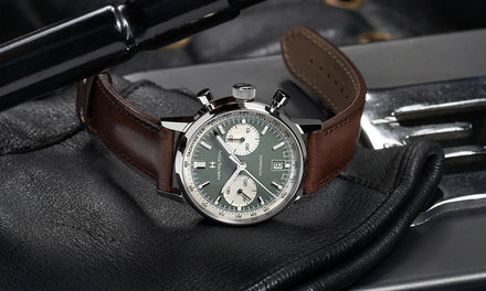 A Hamiltonwatch with a brown leather strap and gray dial with two white subdials sitting on a piece of black leather