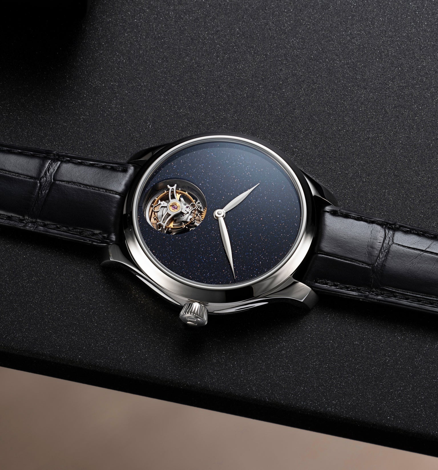 Steel watch with dark blue speckled dial, exposed tourbillon at 9 o'clock, and black leather strap.