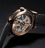 Rose gold tourbillon watch with open caseback, visible mechanical movement, black leather strap, and diamond-set bezel on dar