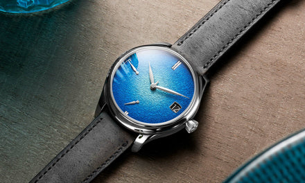 An H. Moser & Cie Endeavor watch on a wooden background with a leather strap and a textured blue dial