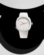 White watch with minimalist dial, silver hour markers, white silicone strap, and orange accent detail on side.
