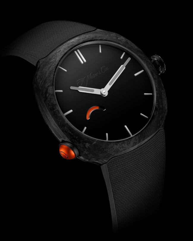 Black watch with textured case, silver hands and hour markers, orange accent details, and black textile strap.