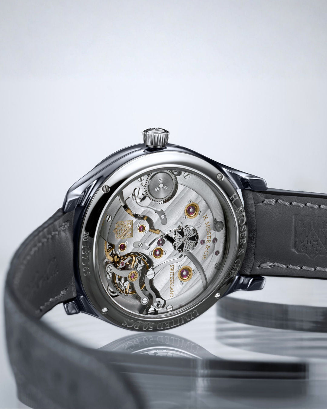 Stainless steel watch with skeleton dial revealing visible gears, tourbillon mechanism, and gold-accented components on black