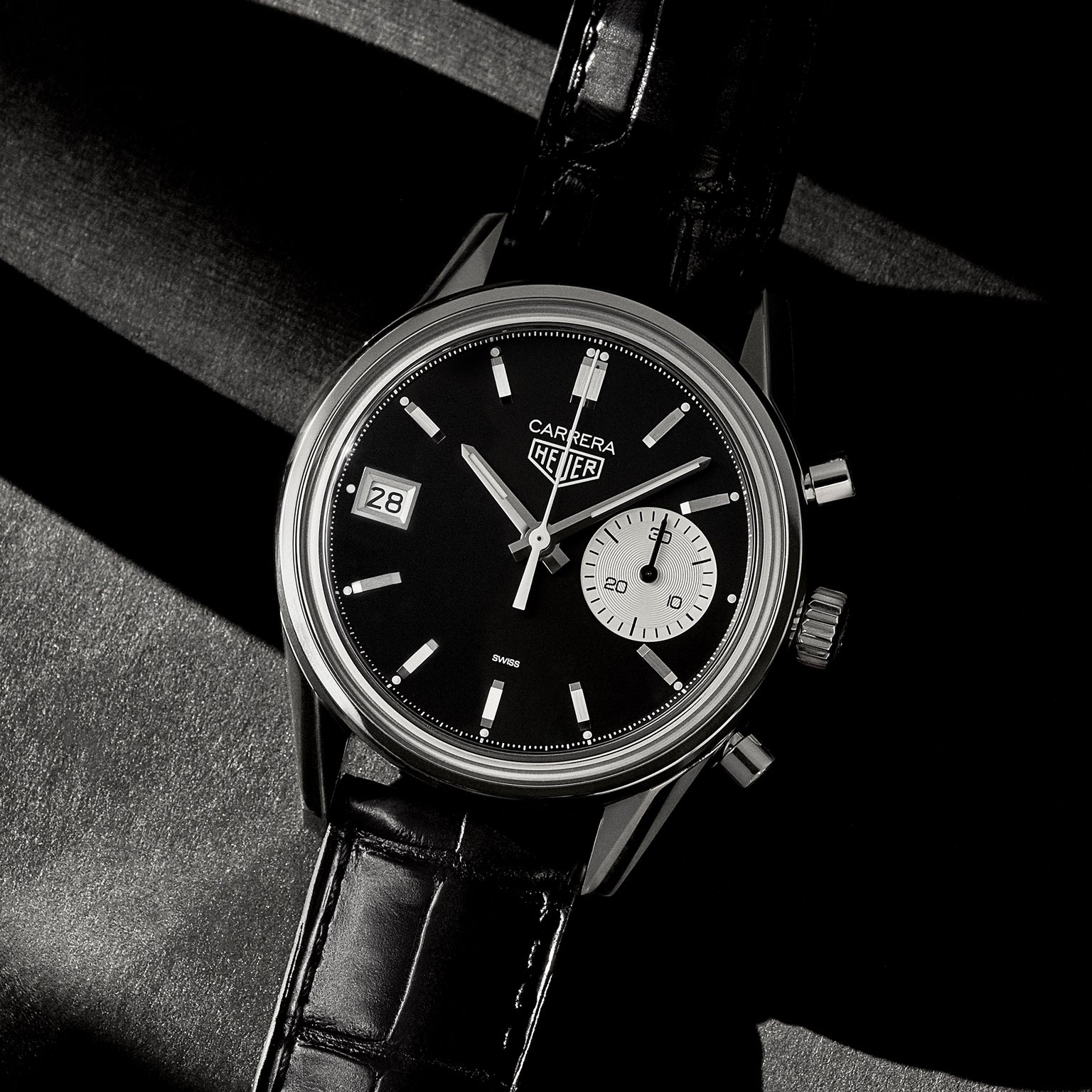 The TAG Heuer Carrera Dato Limited Edition for HODINKEE features a black dial, black leather strap, date at 9 o’clock, and small seconds at 3 o’clock—a striking limited edition timepiece captured in dramatic lighting.