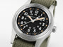Hamilton watch with black dial and green strap on a white background