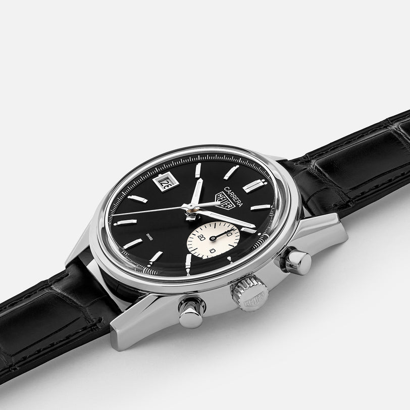 The TAG Heuer Carrera Dato Limited Edition For HODINKEE features a black dial with silver markers, small seconds subdial, date window, and black leather strap, shown against a light background—a distinctive limited edition from TAG Heuer.