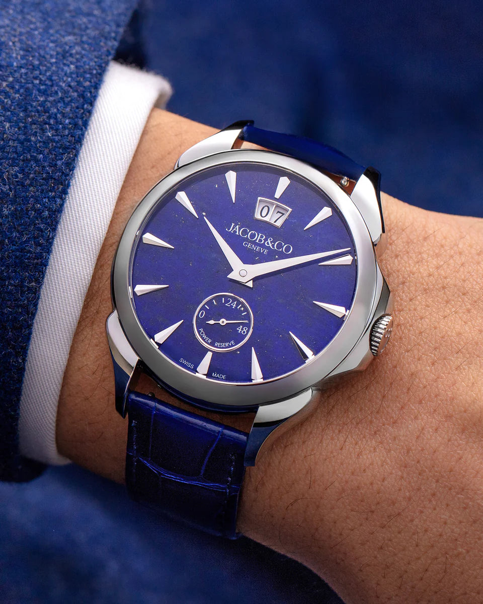 Jacob & Co stainless steel watch with deep blue dial, white hour markers, date window, and blue leather strap on wrist.