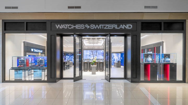 Front view of a Watches of Switzerland store with glass doors and luxury watch displays inside.