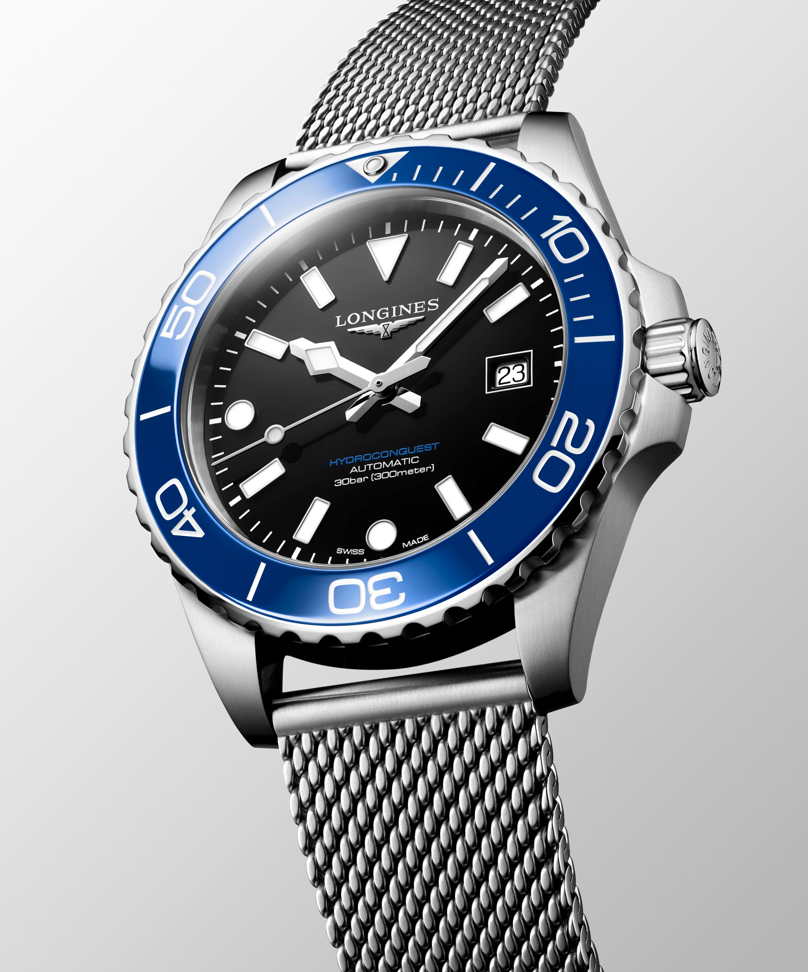 Longines watch with blue bezel and silver mesh band on gray background