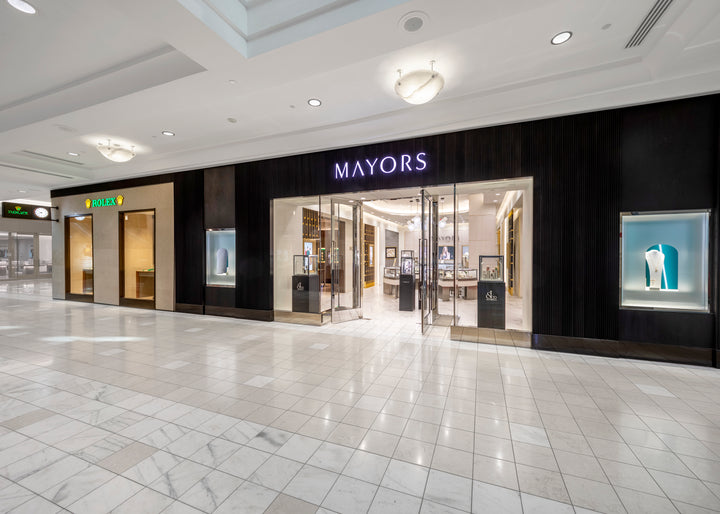 Exterior view of MAYORS jewelry store in a shopping mall, with bright displays and glass doors.