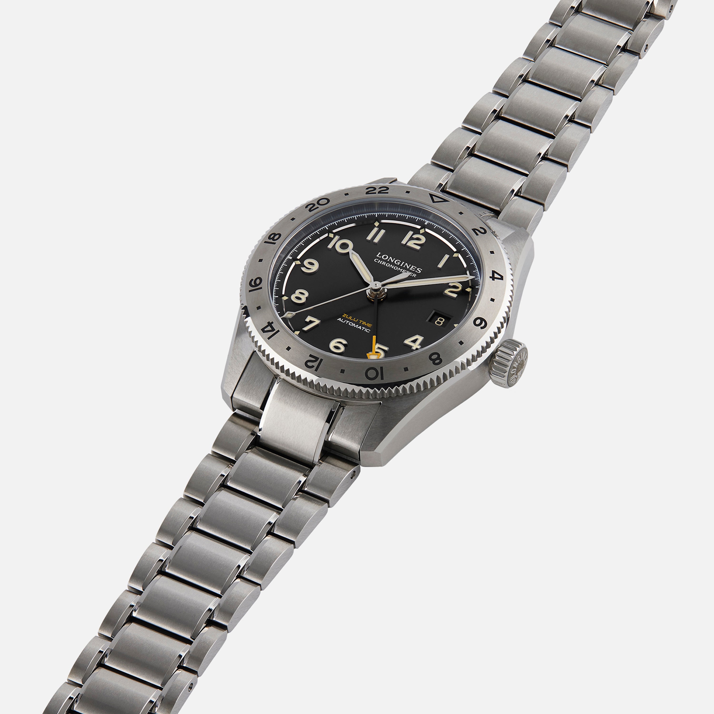 The Longines Spirit Zulu Time Limited Edition For Hodinkee is a stainless steel wristwatch featuring a black dial, silver hour markers, and a metal link bracelet, shown here on a white background.